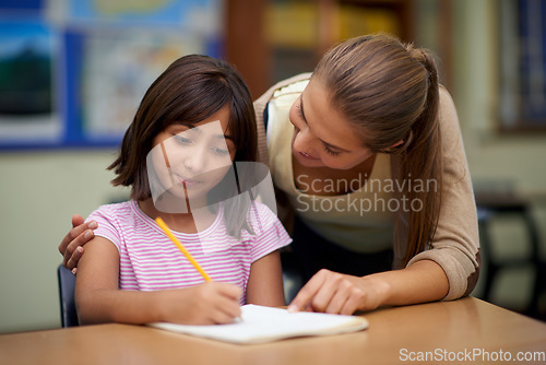 Image of School, education or teaching with a student and teacher in a classroom together for writing or child development. Study, scholarship and learning with a woman educator helping a girl child in class