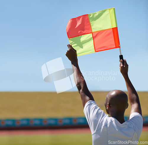 Image of Flag, foul and man soccer referee in football match or game wave to stop play during sport training or workout. Hand, sports and person or assistant official raise or signal mistake in sky background