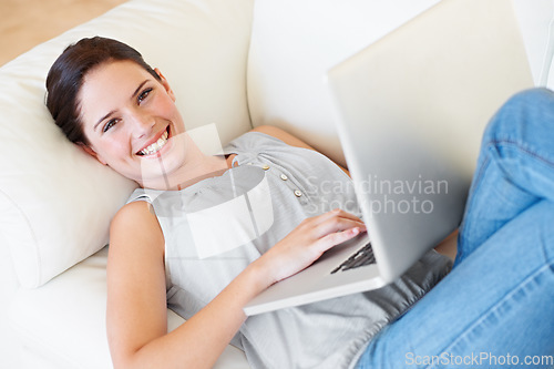 Image of Portrait, happy woman and relax with laptop on sofa with social media and reading in her home. Lying down, smile and face of female online in living room with subscription service and entertainment