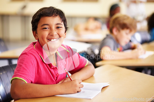 Image of Education, learning and portrait of kid in classroom, smile and writing in book at Montessori school. Happy face, students at desk in class and studying, child development and kids in study or test.