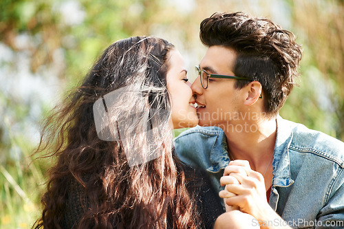 Image of Park, love and couple kiss in nature for romance, summer and valentines celebration in outdoor sunshine. Young people or woman and partner relax in garden for countryside date together with smile