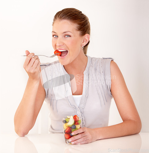 Image of Woman, eating portrait and fruit salad in a studio with happiness from healthy breakfast and food. Smile, young female person and diet nutrition of a model with organic fruits for wellness and health