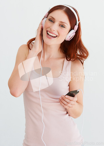 Image of Woman, headphones and smile in portrait for music, streaming and happiness by wall background. Girl, student or isolated model with smartphone for audio app, sound and internet radio with listening