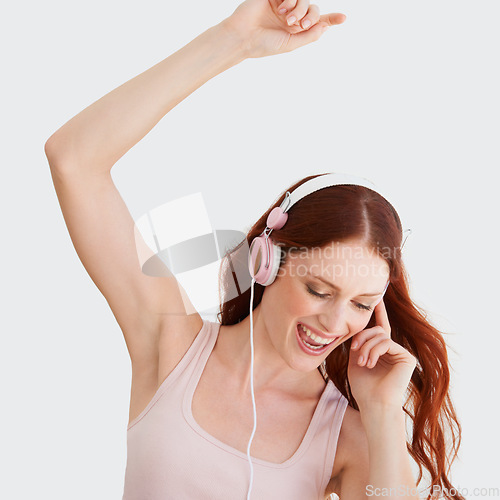 Image of Young woman, headphones and dance in studio with music, streaming and happiness by wall background. Girl, student or isolated model with listening to audio app, sound and internet radio for dancing