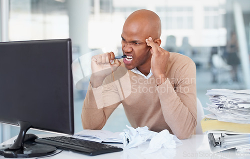 Image of Stress, computer and burnout with a business man biting his pen at a desk in the office working on a problem. Audit, tax and anger with a frustrated young male employee suffering from anxiety at work