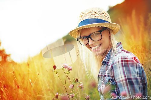 Image of Lens flare, countryside and portrait of woman with flowers in field for freedom, wellness and fresh air outdoors. Nature, summer and happy female person in natural meadow for relaxing, calm and peace