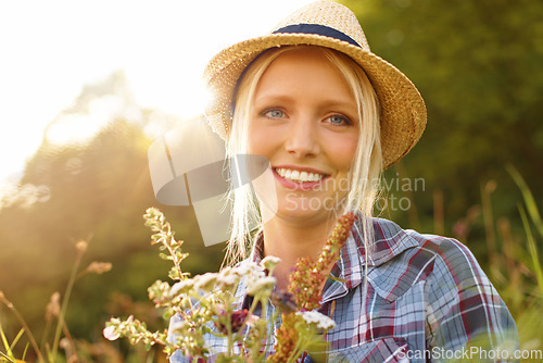 Image of Countryside, flowers and portrait of woman in field for sustainability, wellness and fresh air outdoors. Nature, summer and face of hipster person in meadow to relax, calm and peace with lens flare