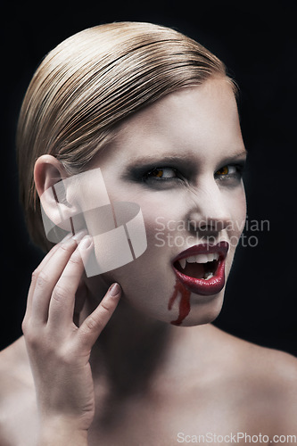 Image of Portrait, blood and a female vampire in studio on a dark background for halloween or cosplay. Fantasy, horror or scary with an attractive young woman monster posing as an evil and feminine creature