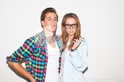 Image of Party portrait of hipster couple smoking with glasses, gen z fashion and university culture in youth. Cigarettes, woman and man at fun college event, cool people on white wall background with smoke.