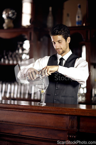 Image of Bartender man, glass and mixing cocktail at bar for service, drink or hospitality at party, club or event. Male server, barman or waiter with alcohol, spirit or mixer for presentation at restaurant