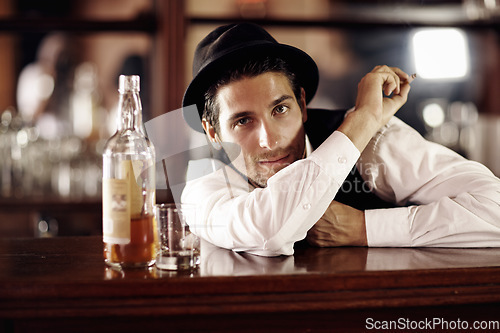 Image of Bartender man, portrait and bottle with smoking, service, drink at party, club or event. Male server, barman or waiter with glass for alcohol, spirit or whiskey to relax after work at restaurant