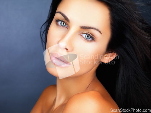 Image of Beauty, skincare and healthy clean skin of a beautiful young woman with gorgeous blue eyes. Face portrait of a confident, aesthetic and sensual woman posing against a blue studio background