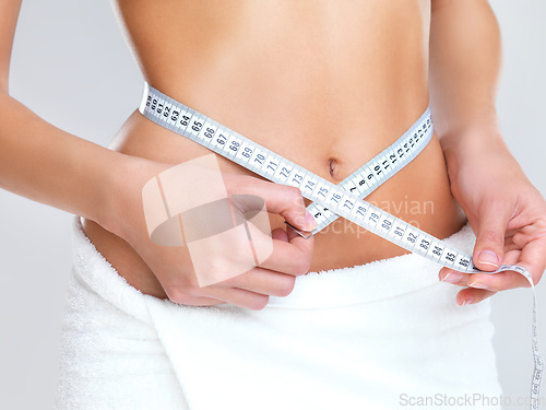 Image of Woman, hands and tape measure on stomach for lose weight, diet or slim body against a grey studio background. Hand of female person or model measuring waist in weightloss, results or healthy wellness