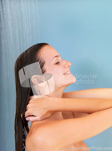 Image of Happy, beauty and skincare of woman in shower for bathroom, hygiene and luxury. Wellness, spa and dermatology with face of girl for facial, cleaning and hydration isolated on blue background studio