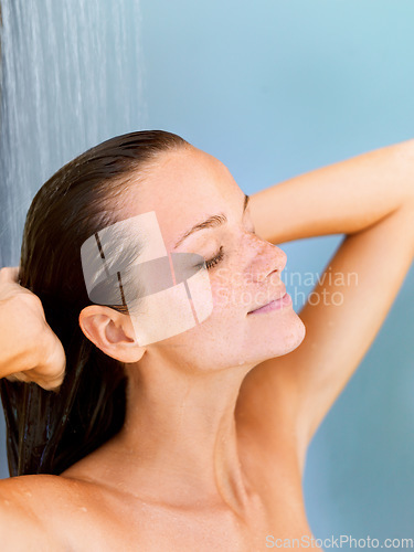 Image of Hair, beauty and water with woman in shower for shampoo, hygiene and luxury. Wellness, spa and dermatology with face of girl for facial, cleaning and skincare isolated on blue background studio