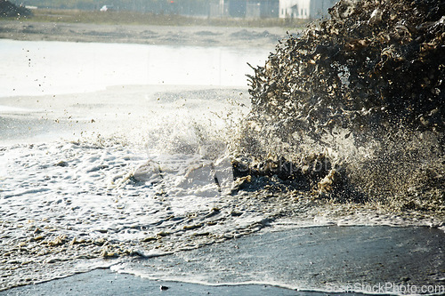 Image of Pollution, sewer and waste in water to ocean from industrial for construction, pipeline and danger. Environment, texture and industry with wave from sewage on shoreline for stream, foam and mud