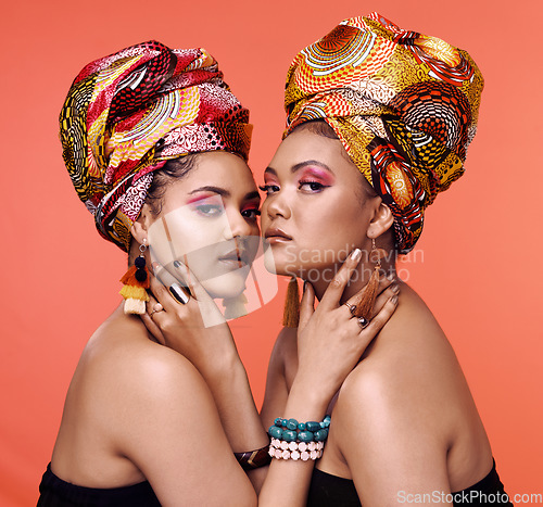 Image of African fashion, cosmetics and portrait of women on orange background with accessory, makeup and beauty. Glamour, luxury and female people in exotic jewelry, traditional style and scarf in studio