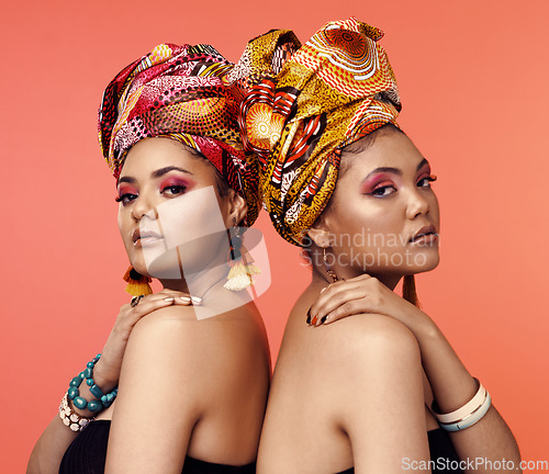 Image of African fashion, cosmetics and portrait of women on orange background with accessory, makeup and beauty. Glamour, luxury and female people in exotic jewelry, traditional style and scarf in studio