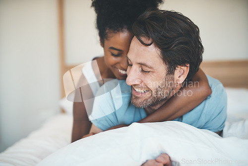 Image of Happy couple, bed and smile in hug for morning, relax or bonding relationship at home. Interracial man and woman smiling and hugging in joyful happiness for relaxing weekend together in the bedroom