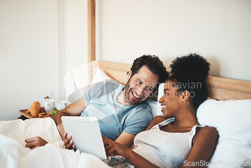 Image of Happy couple, tablet and laughing on bed for joke, funny entertainment or online streaming at home. Interracial man and woman person on technology in relax for morning or social media in the bedroom