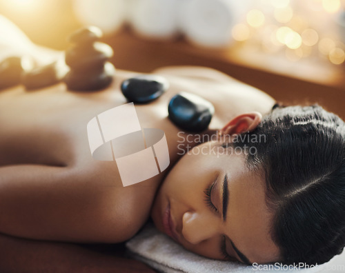 Image of Woman, relax and sleeping in rock massage at spa for skincare, beauty or body treatment at resort. Calm female asleep in relaxation with hot rocks or pile on back in therapy, zen or wellness at salon