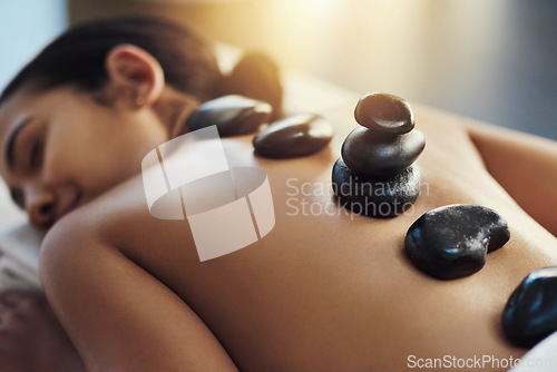 Image of Happy woman, sleeping and hot rock massage at spa for skincare, beauty or body treatment at resort. Calm female asleep with heated rocks on back for healthy physical therapy, zen or wellness at salon