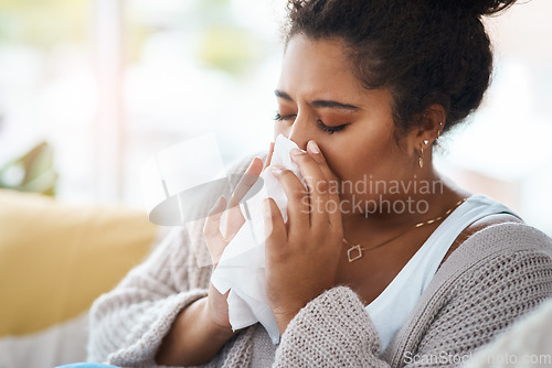 Image of Sick, cold and a woman blowing nose on sofa with covid, virus or allergies in a house. Flu, healthy and a young lady with an allergy, sinus problem or sneezing into a tissue on the living room couch