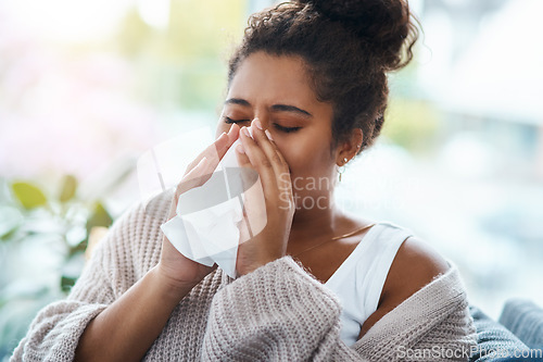 Image of Sick, virus and a woman blowing nose on the sofa with covid, hay fever or allergies in a house. Flu, young lady and an allergy, sinus problem or sneezing into a tissue on the living room couch