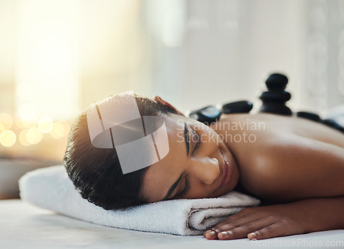 Image of Happy woman, relax and sleeping in massage at spa for skincare, beauty or body treatment. Calm female asleep in relaxation with hot rocks or pile on back in therapy, zen or wellness at salon resort