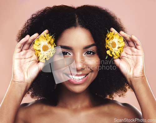 Image of Portrait of happy woman, hair care and beauty with yellow flowers on studio background. African model, natural skincare and daisy plants in afro for sustainable cosmetics, floral aesthetic and smile