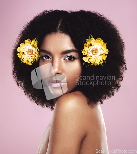 Image of Portrait, woman and flowers in hair in studio, pink background and eco friendly makeup, beauty or natural skincare. Face of serious african model, floral cosmetics or afro for sustainable dermatology