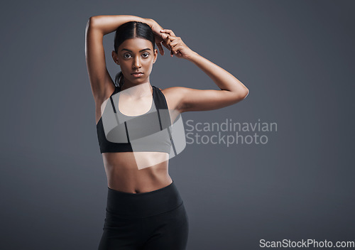 Image of Portrait, space and stretching with an athlete woman in studio on a gray background for fitness or health. Exercise, workout or warm up and an attractive young female model training with mockup