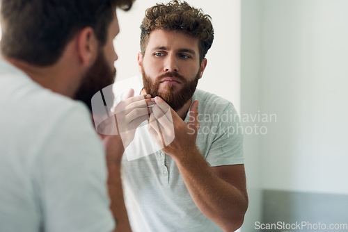 Image of Face, beauty and beard with a man in the bathroom of his home in the morning for fresh hygiene. Mirror, reflection and care with a handsome young male person checking his skin for facial treatment