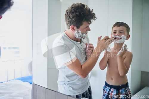 Image of Father, child and learning to shave in bathroom, having fun or bonding together. Smile, dad and teach kid with shaving cream on face, playing or cleaning, hygiene or enjoying hair removal with care.