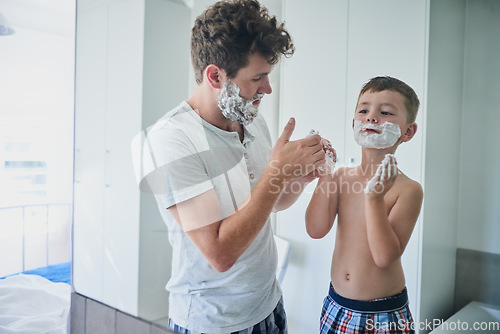 Image of Father, kid and learning to shave in bathroom, education and bonding together. Care, dad and teaching child with shaving cream on face, playing or cleaning, hygiene or enjoying hair removal in home.