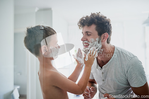 Image of Child, father and learning to shave, smile and bonding together in home bathroom. Happy, dad and teaching kid with shaving cream on face beard, playing or cleaning, hygiene or enjoying hair removal.