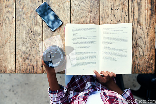 Image of Woman, hands and book of student reading with coffee for literature on wooden table above at cafe. Top view of female person hand and story novel for knowledge, language or information at coffee shop