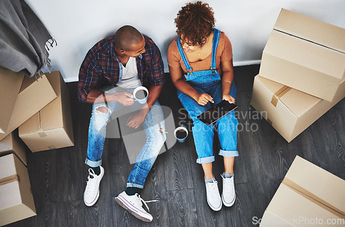 Image of Boxes, new home and couple with a tablet planning on their living room floor together with coffee. Technology, real estate and top view of young people doing online property research in a house