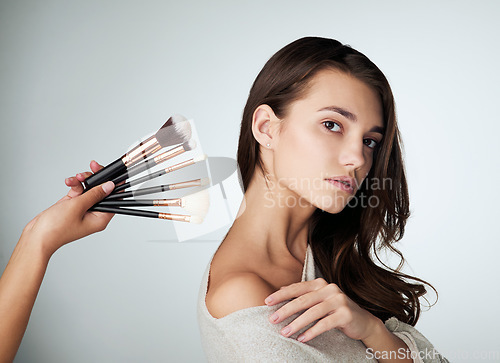 Image of Makeup, face brush and beauty of a woman in studio with natural glow on skin. Portrait of female person on a grey background with a hand for cosmetology tools, powder cosmetics and facial dermatology