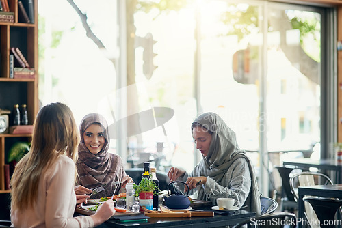 Image of Friends, happy and Muslim women in restaurant, eating and talking together. Lunch, smile and Islamic girls, group or people chatting, conversation and discussion for social meeting, bonding and food.