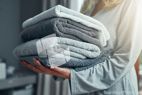 Image of Laundry, cleaning and a woman with a pile of towels in her home for hygiene or a spring clean day. Hospitality, service and a female cleaner carrying a stack of fresh or clean fabric in a hotel room