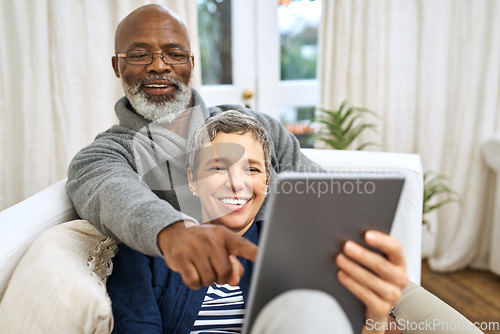 Image of Technology, senior couple with tablet and on sofa happy in living room of their home. Social media or streaming, retirement or relax and happy married people on couch laughing with digital device