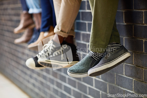 Image of Brick wall, students feet and friends outdoor on university campus together with sneakers. Relax, youth and foot at college with people legs ready for education, study and urban shoes while sitting