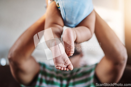 Image of Closeup, legs and baby with father, love and playing with joy, happiness and bonding in the lounge. Zoom, dad and infant in the air, home and games with child development, fun and family on a couch