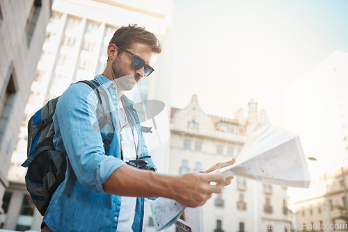 Image of Tourist, man and a map in a city for travel on a street with a backpack for location or direction. Male person with paper for navigation outdoor on urban road for adventure, journey or vacation