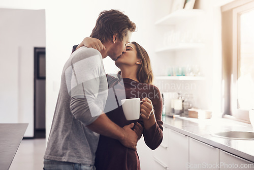 Image of Love, intimate and kiss with a couple in the kitchen of their home together in the morning for romance. Kissing, passion or sexy with a man and woman in their house for romantic intimacy or bonding