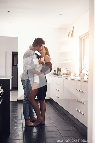 Image of Love, passionate and a couple kissing in the kitchen of their home together in the morning for romance. Kiss, passion or sexy with a man and woman bonding in a house during an intimate moment