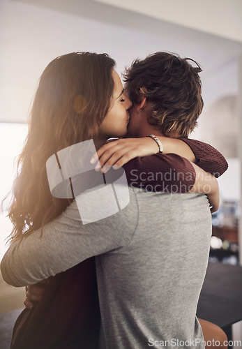 Image of Couple, hug and kiss in home for love, care and bonding for quality time together with trust, loyalty and happiness. Happy young man, woman and kissing for affection, romance or intimate relationship