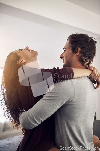 Image of Laughing couple, love and hug in apartment for care, quality time and bonding together for commitment to relationship. Happy young man, woman and hugging for romance, smile and relax with joy at home