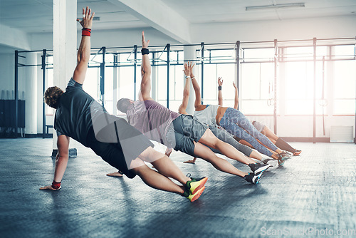 Image of Fitness, group class and athletes doing a exercise in the gym for health, wellness and flexibility. Sports, training and people doing side plank exercise challenge together in sport studio or center.